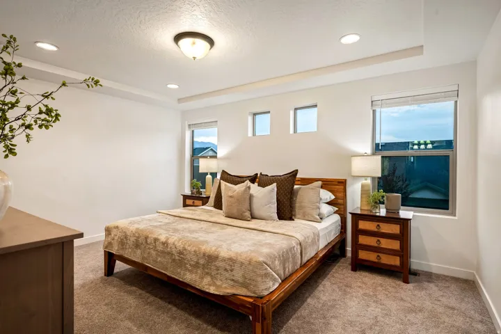 Tray ceiling with recessed lighting, flush-mount ceiling light, broad window, two high-set windows, and plush carpet flooring