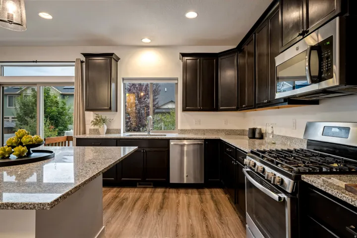 Kitchen featuring dark wood cabinetry, light-toned countertops, wood-finish flooring, and stainless steel appliances
