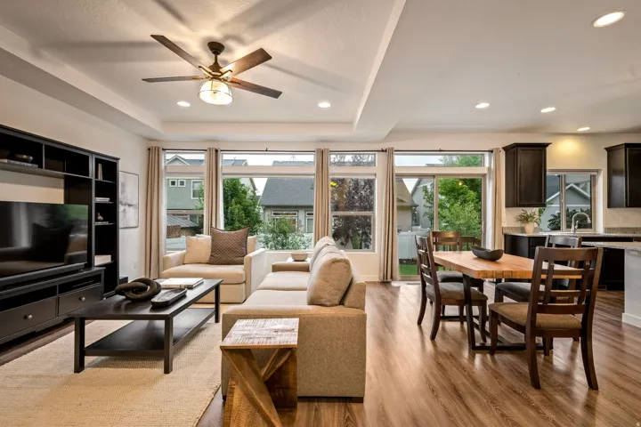 Recessed lighting, wood-finish flooring, tray ceiling, dark wood built-in media center, and a multi-pane sliding glass door