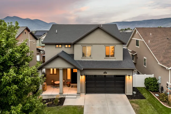 Stucco exterior with a covered porch, attached garage, and mountain backdrop