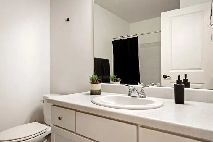 Spa-inspired bathroom featuring a curved vanity with dual-sink configuration, quartz countertop, and chrome faucetry
