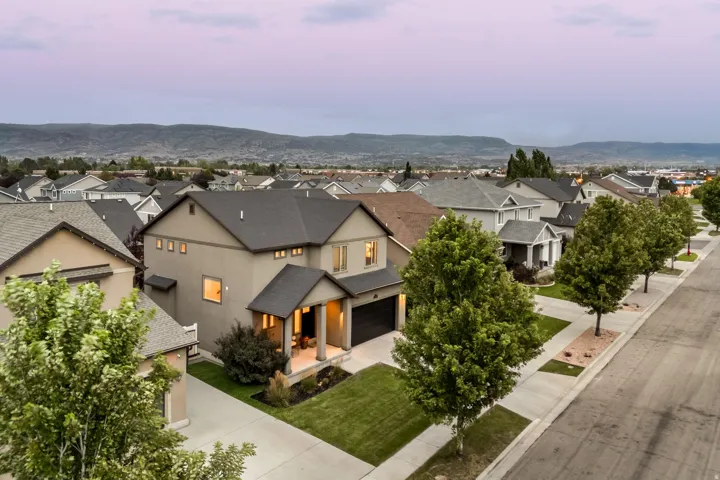 Modern two-story residence featuring a mixed-material exterior with stone and stucco finishes, dark architectural roofing, and recessed entry lighting