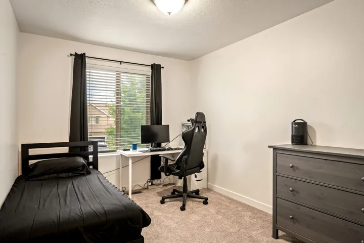Versatile bedroom featuring neutral carpeting, large windows with black drapery hardware, and ample natural light