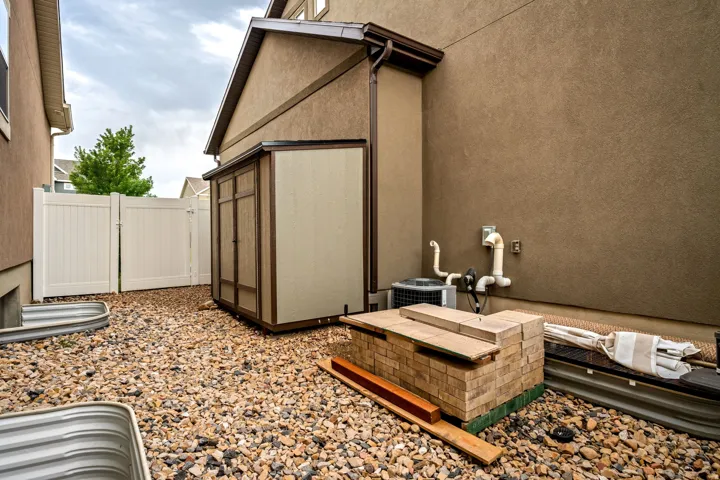 Gravel ground cover with a white privacy fence and a storage shed