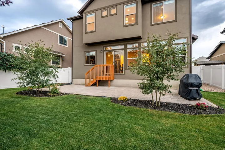 Expansive green lawn with a paver patio and a wooden deck