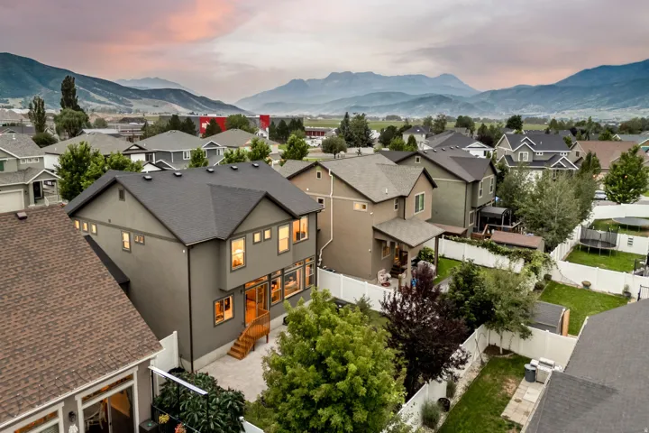 Modern two-story residence with contemporary architectural styling, featuring a dark composite roof, wood-finish entry doors with sidelights, and illuminated windows