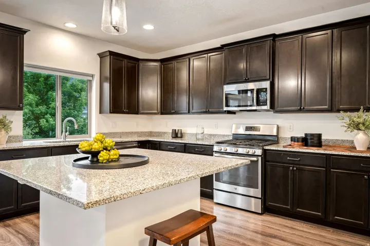 Kitchen featuring an oversized island, dark wood-finish cabinetry, stainless steel appliances, speckled stone countertops, and wood-finish flooring