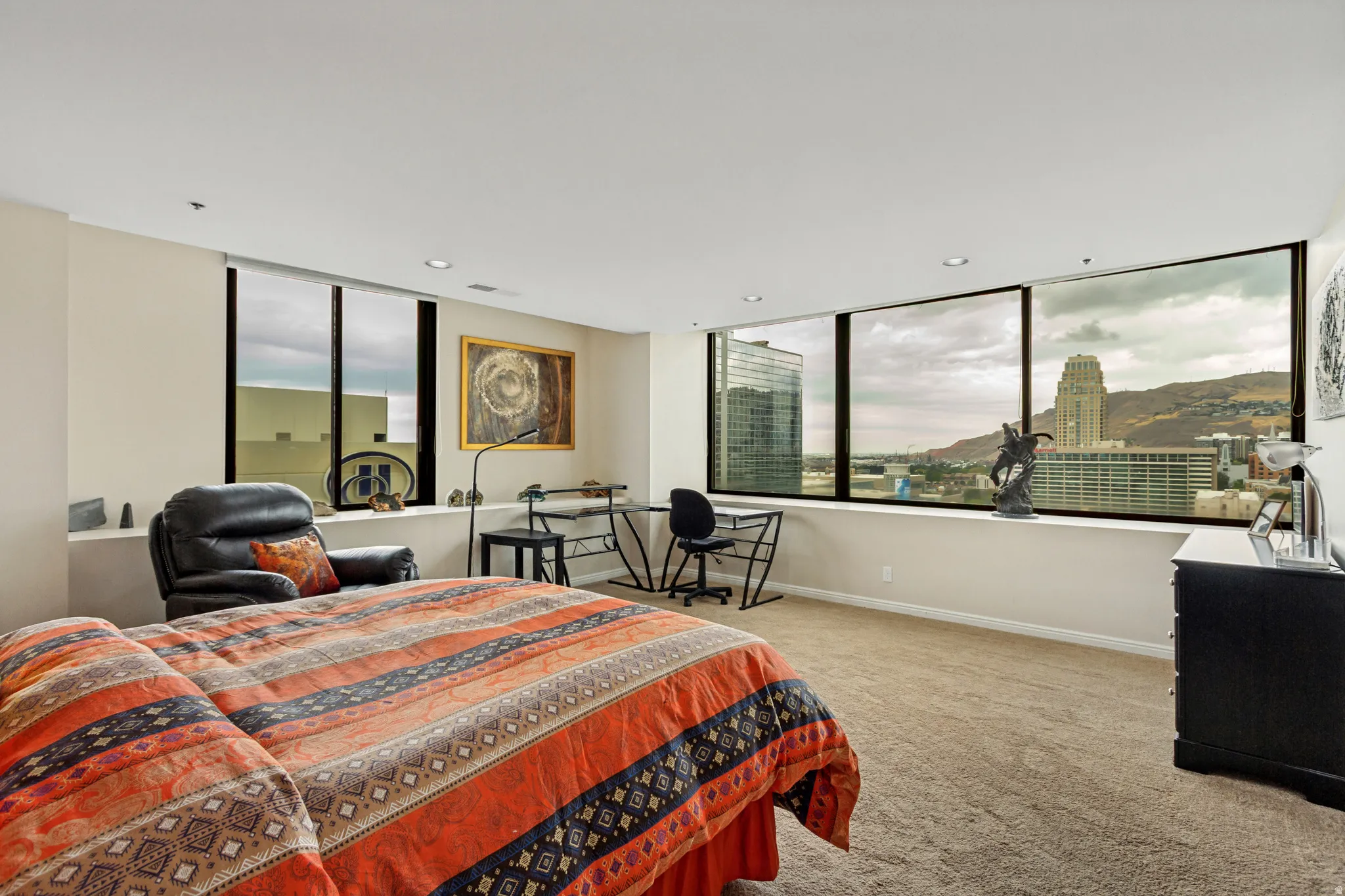 Primary bedroom suite with expansive windows framing panoramic city and hillside vistas, light-filled interior with neutral wall finishes.