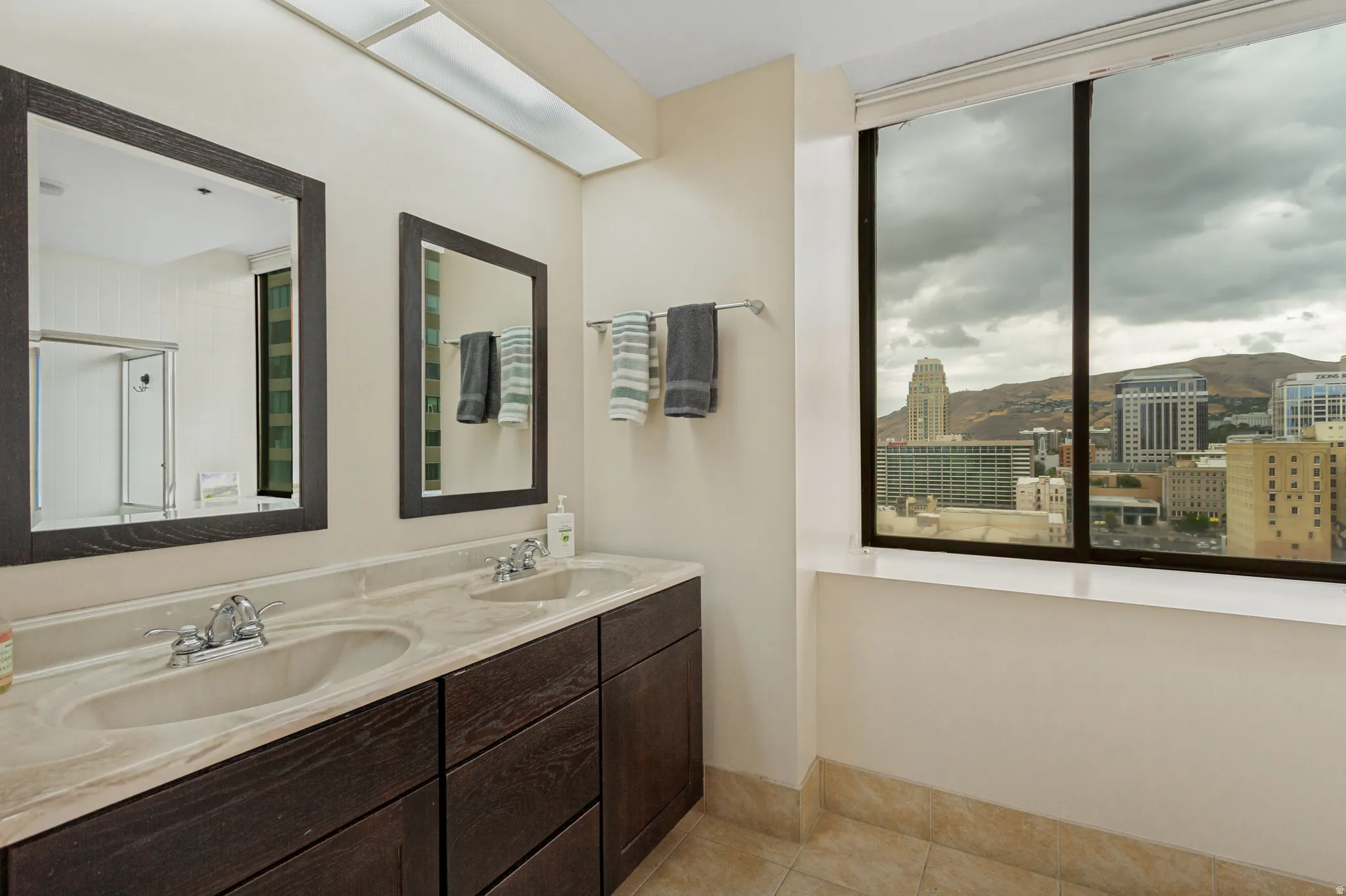 Primary bath also has views, dual framed mirrors, double vanity with integrated sinks, and ample under-counter storage