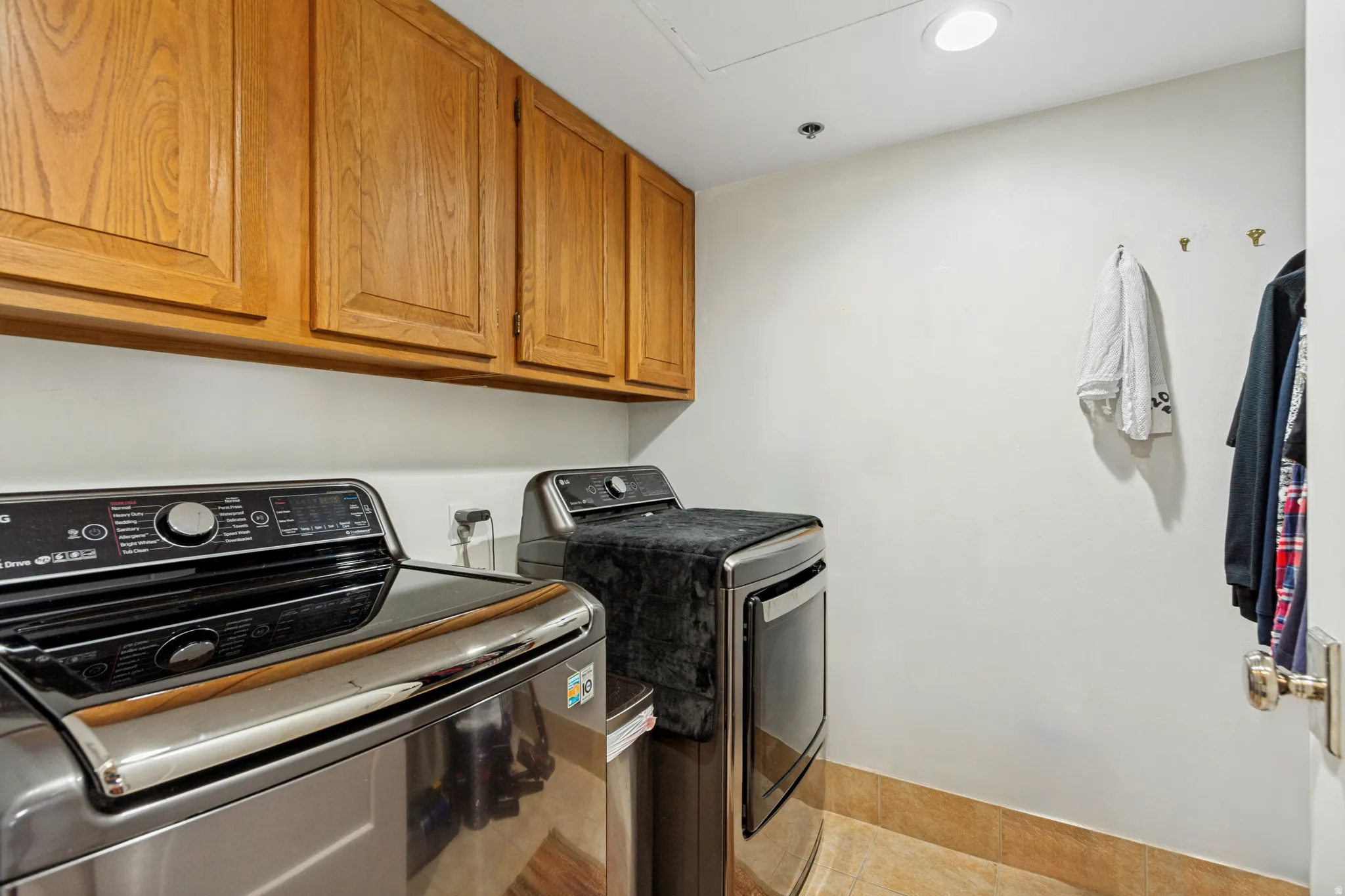Laundry area featuring light wood cabinetry, recessed lighting, and tile flooring