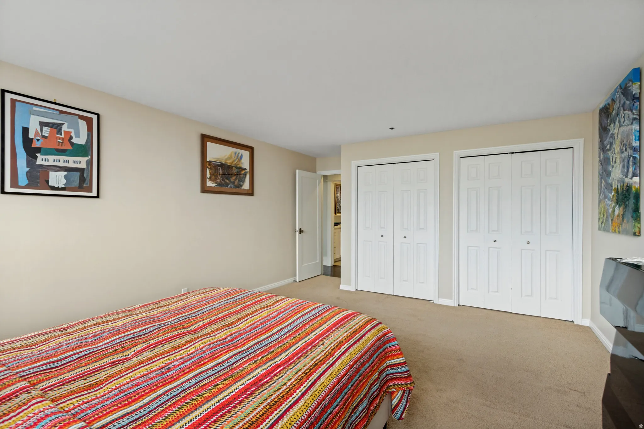 Neutral-toned walls, carpeted flooring, and two sets of bi-fold closet doors