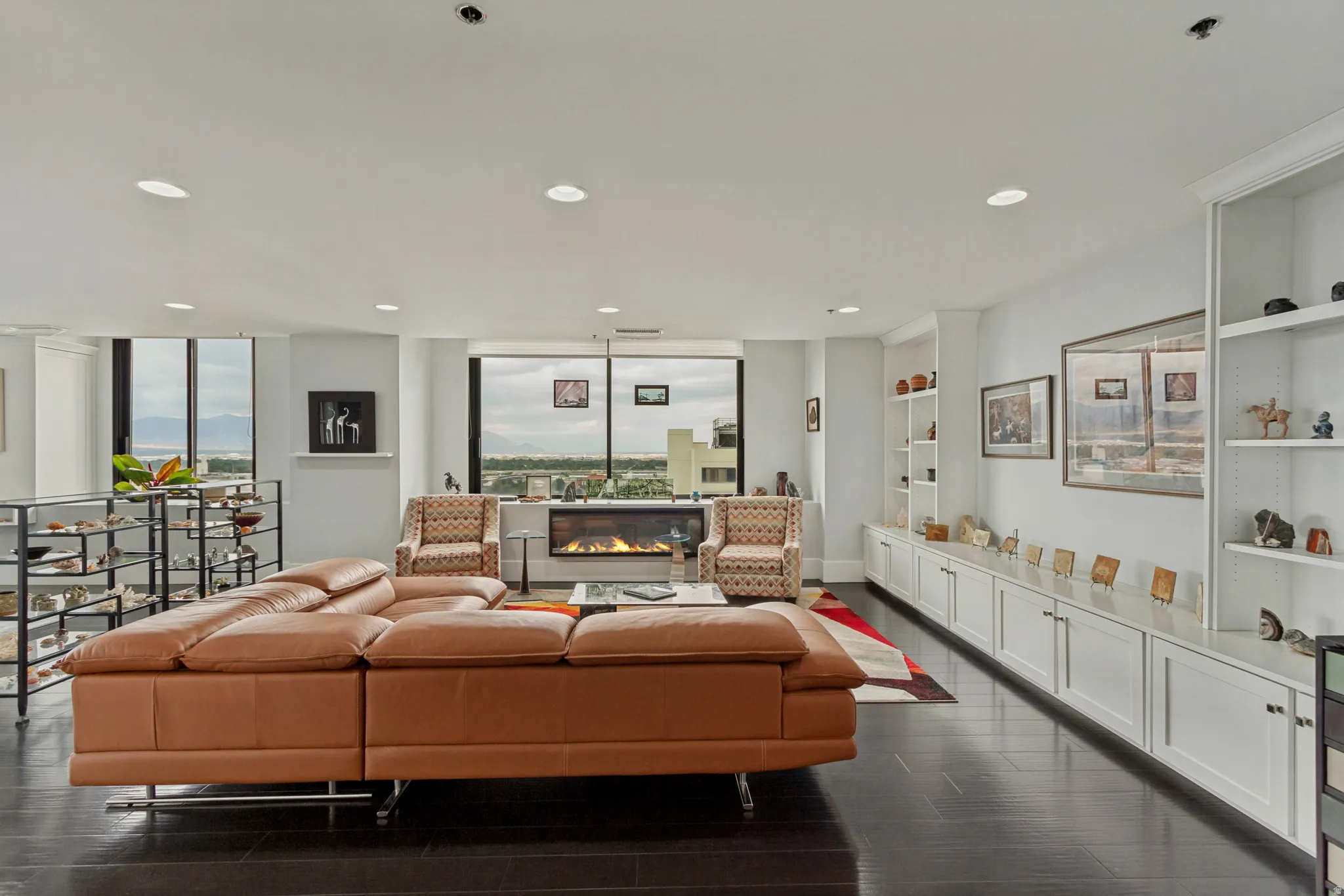 Hardwood flooring, recessed lighting, built-in shelving, built-in cabinetry, and a linear fireplace