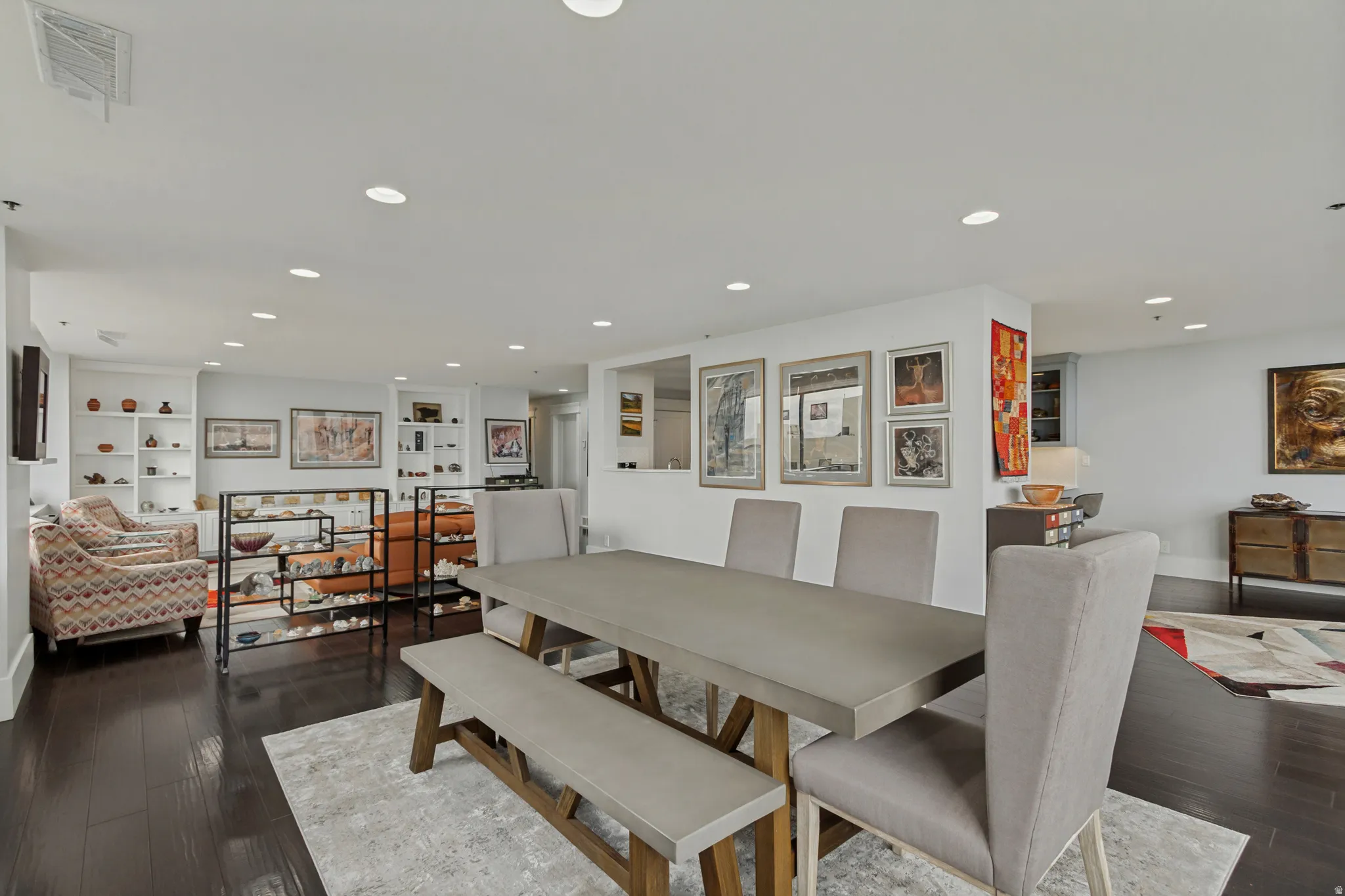 Recessed lighting illuminates the expansive living area with dark wood-finish flooring