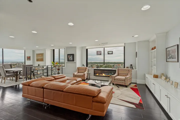 Sophisticated upper floor living room showcasing panoramic windows with S through W vistas, dark wood-finish flooring, and a modern fireplace with linear design
