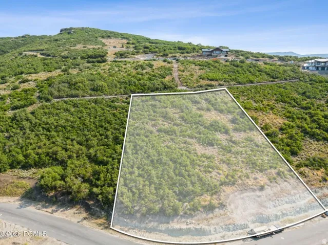 Expansive undeveloped lot with natural terrain, surrounded by a verdant, hilly landscape