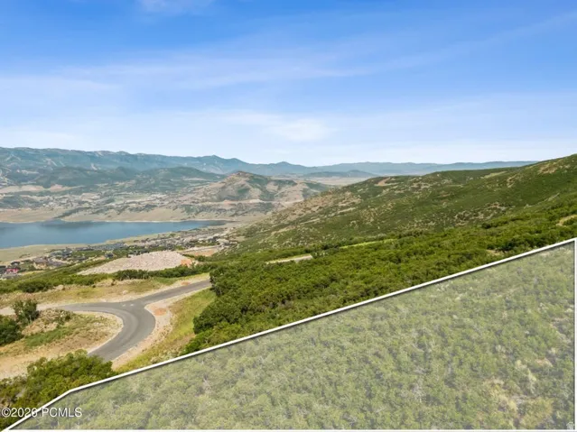Terraced hillside lot with partial lake and mountain scenery, featuring a paved access road