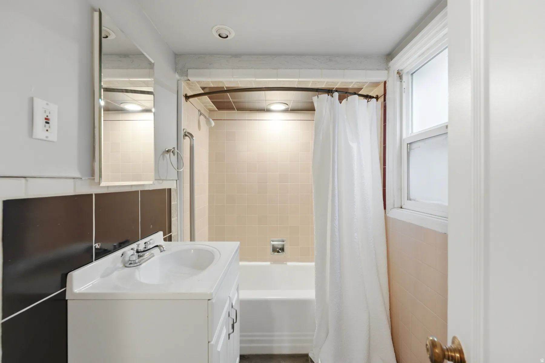 Full bathroom featuring a white vanity with integrated sink, chrome faucet, and a wall-mounted medicine cabinet