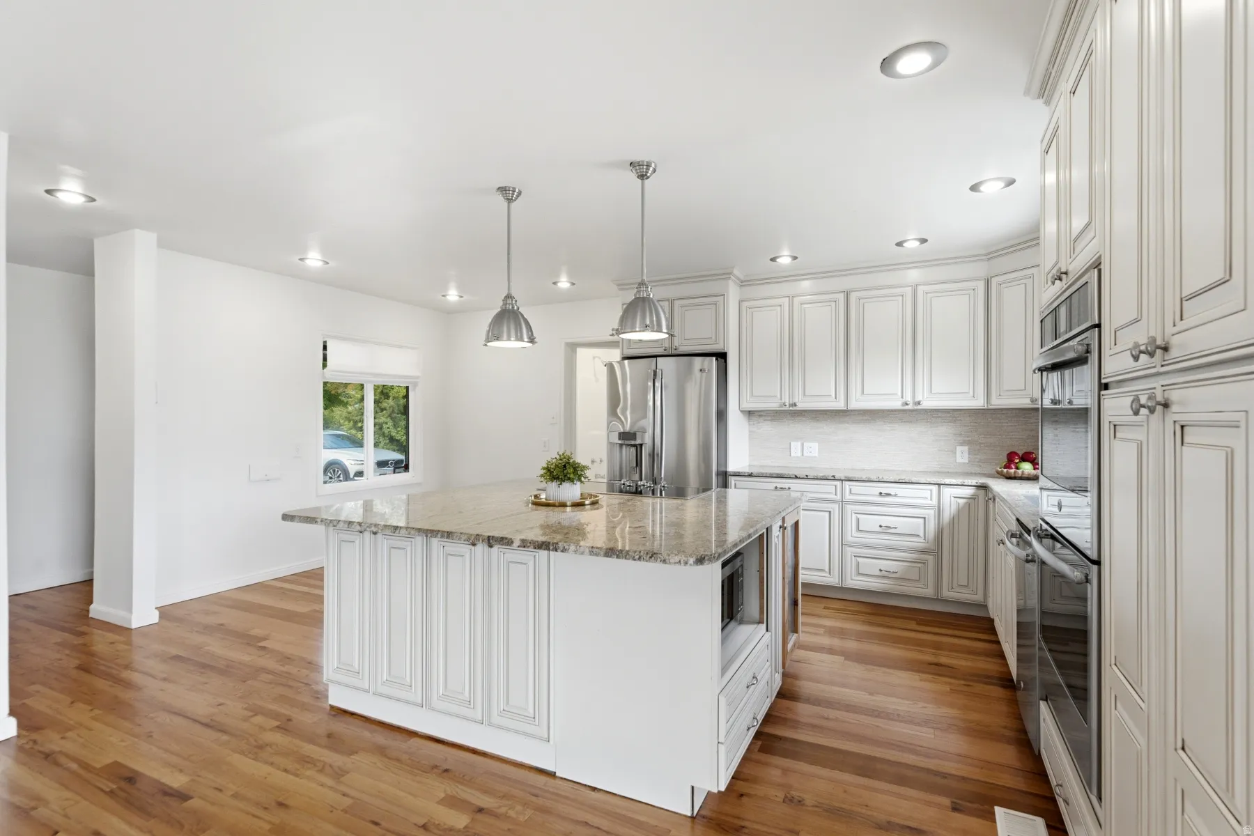 Kitchen featuring a center island with a stone countertop, white cabinetry, stainless steel appliances, wood-finish flooring, and recessed lighting