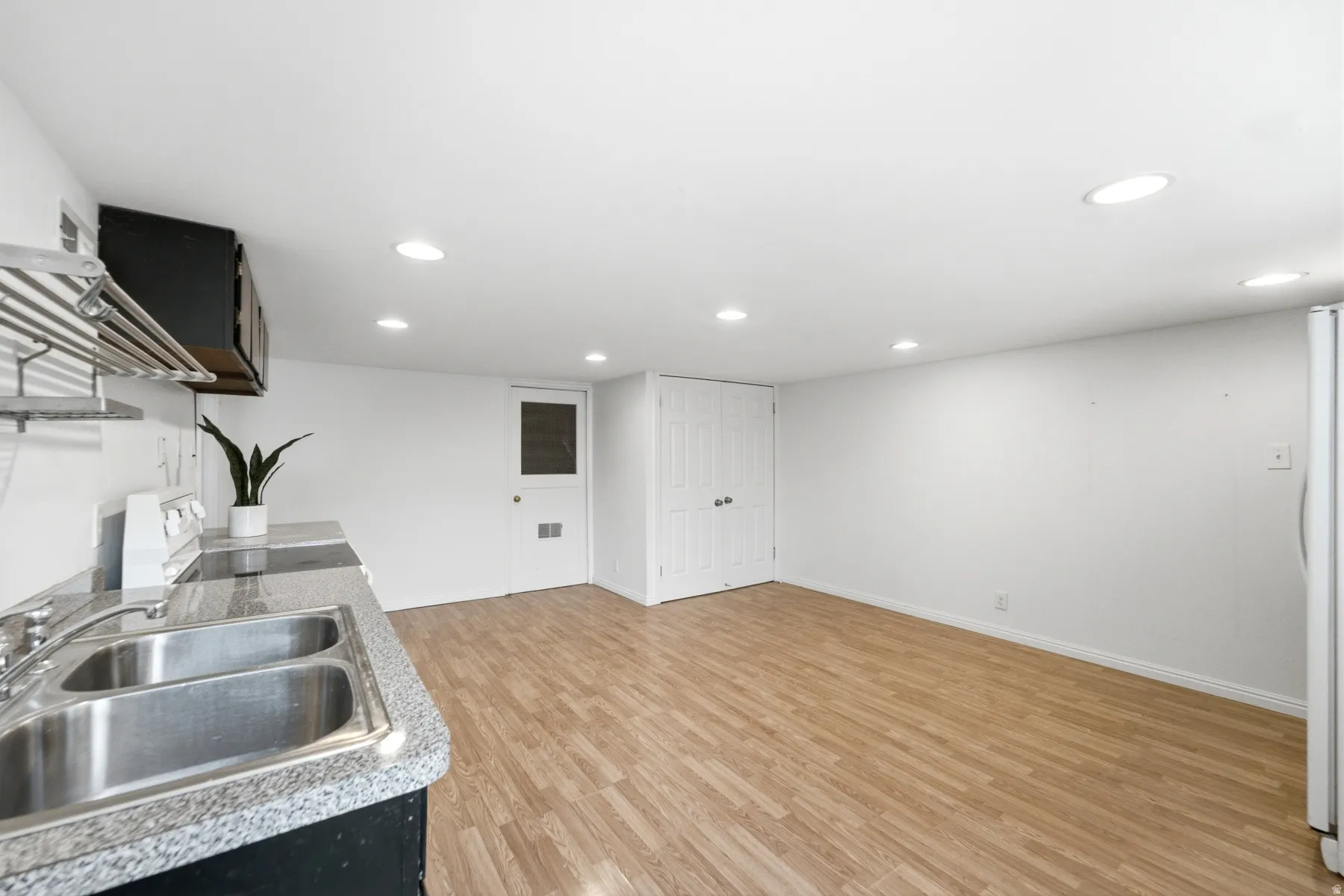 Kitchenette featuring a double basin stainless steel sink with a granite-finish countertop, white electric range, and wood-finish flooring