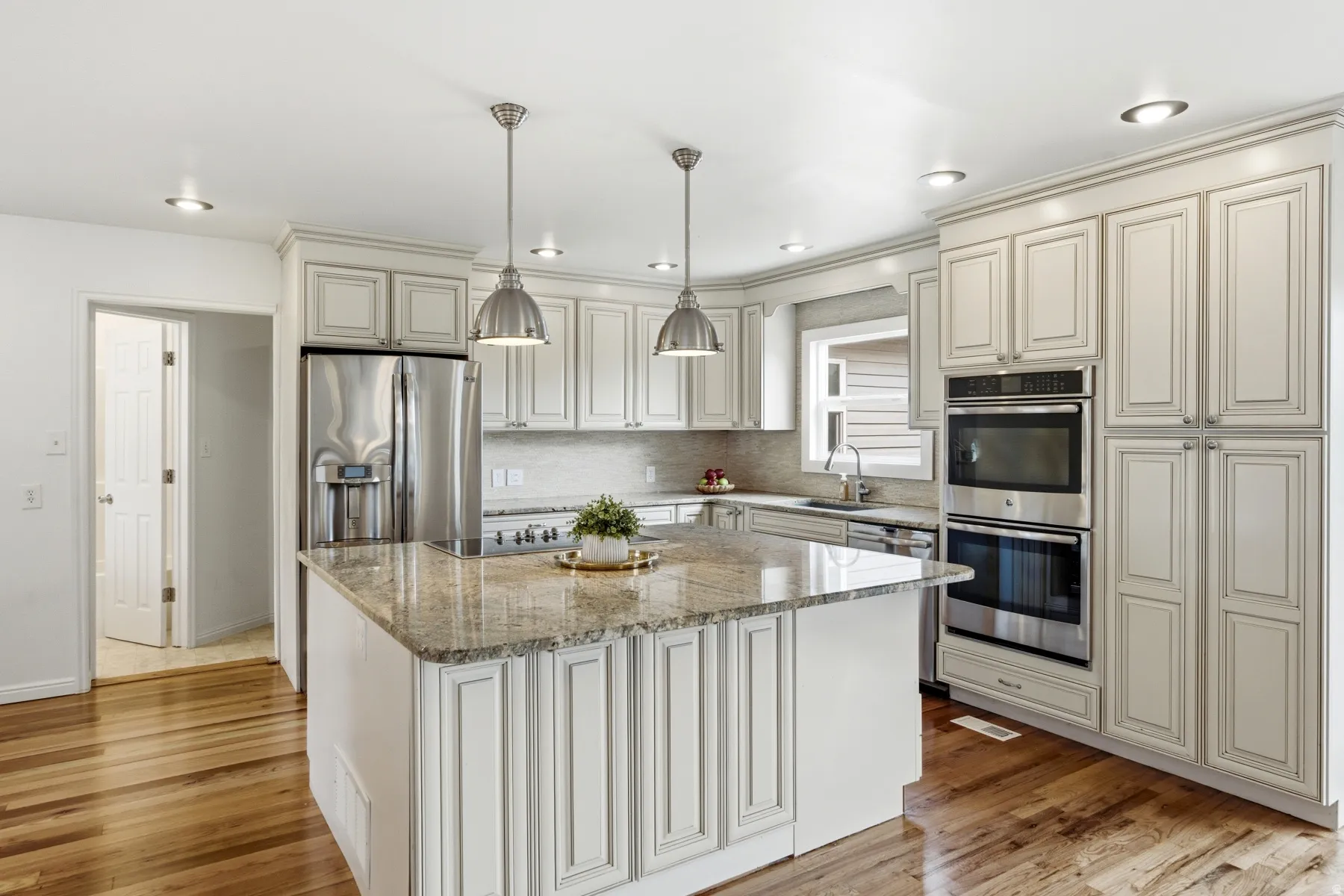 Kitchen featuring white cabinetry, wood-finish flooring, stainless steel appliances, a center island with a stone countertop, and recessed lighting