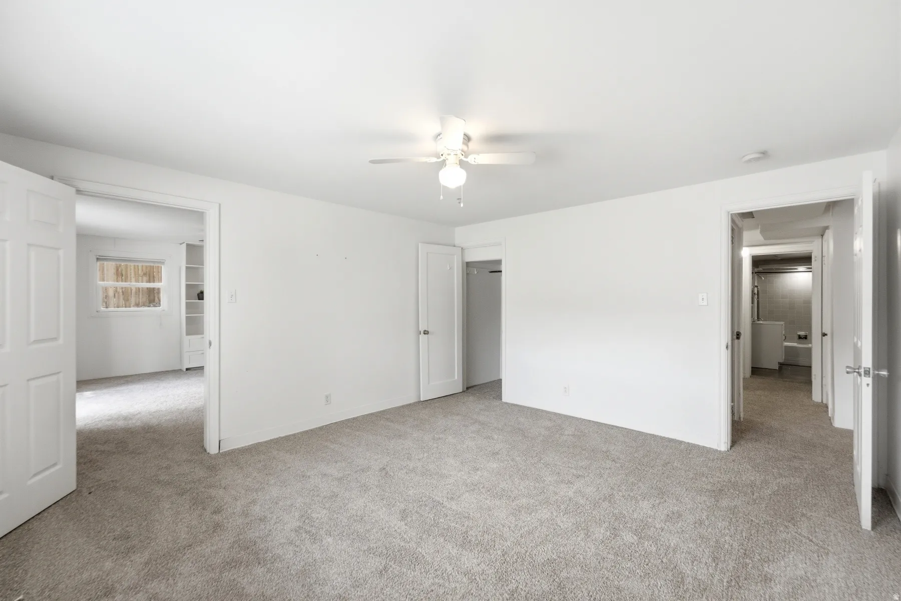 Neutral white walls, gray carpet flooring, and a ceiling fan with integrated lighting