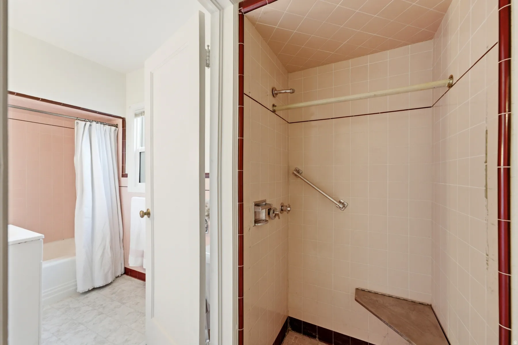 Tiled shower enclosure with built-in bench, grab bar, and wall-mounted fixtures