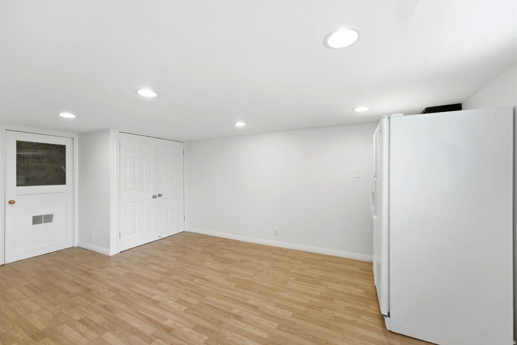 Recessed lighting, wood-finish flooring, and white walls