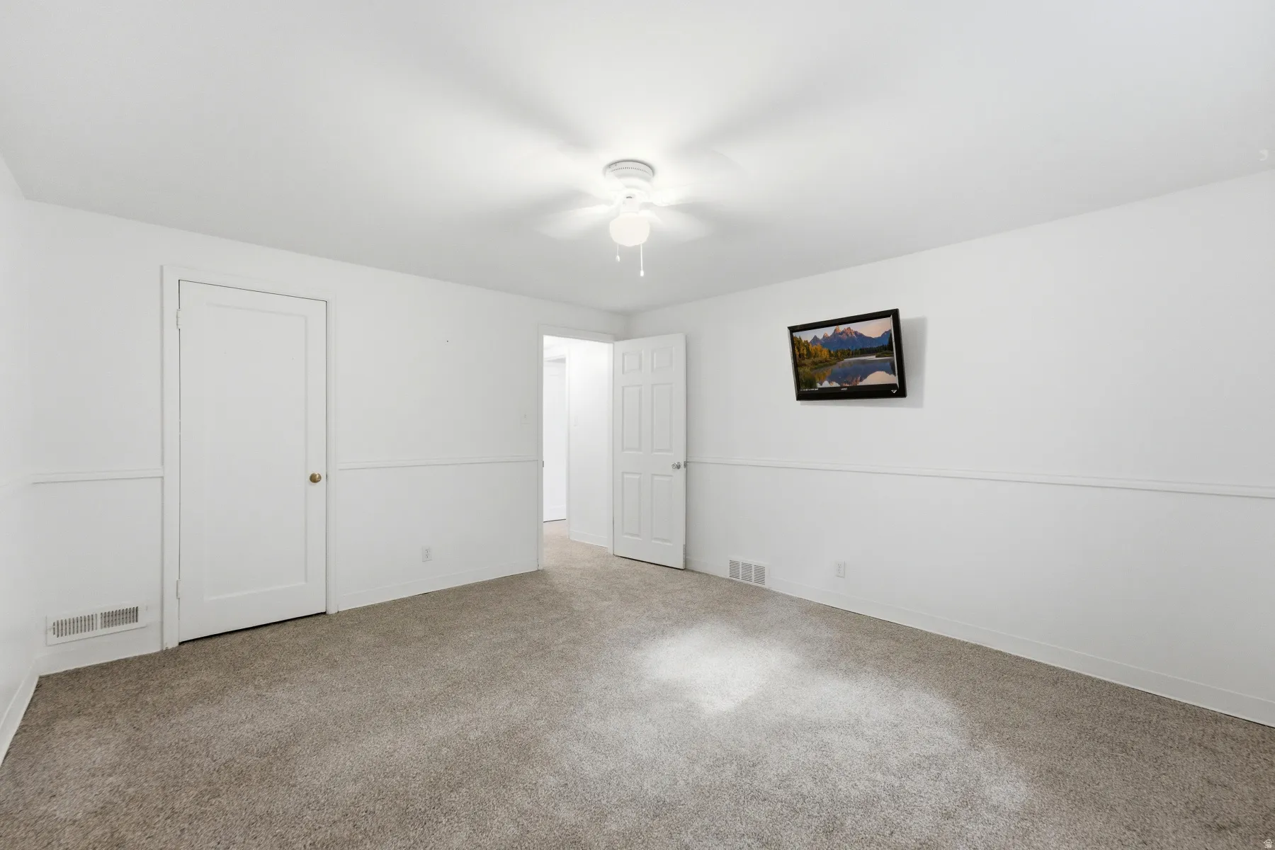 Carpeted flooring with white wall finishes, crown molding, and a ceiling fan with light fixture