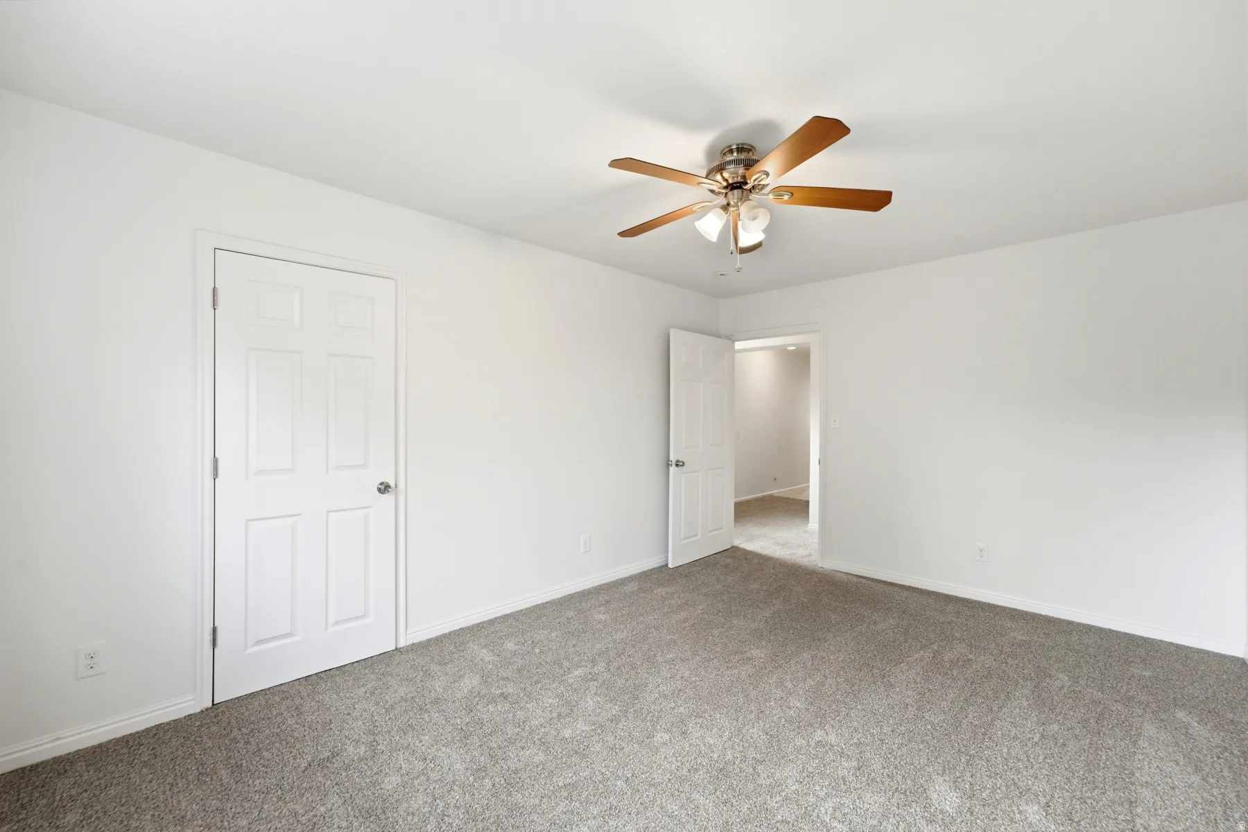 Neutral wall color, ceiling fan with light fixture, paneled doors, and gray carpet flooring