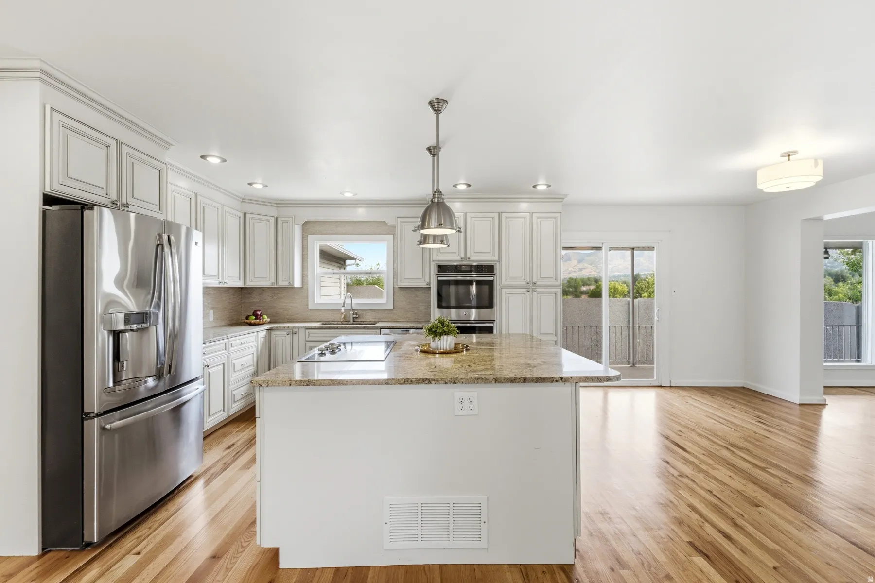 Kitchen featuring white cabinetry, stainless steel appliances, a center island with a cooktop, and wood-finish flooring