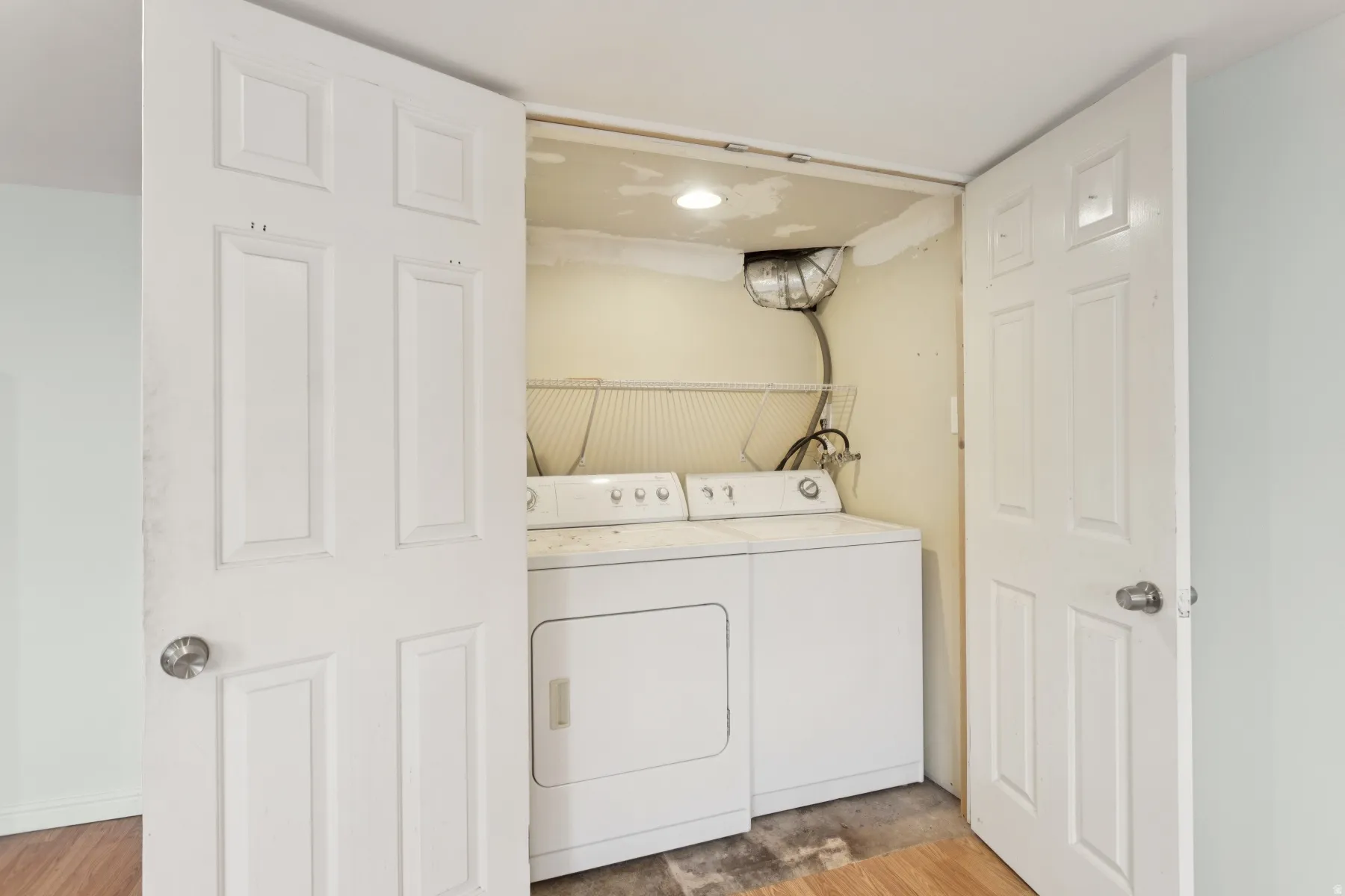 Laundry area featuring a stacked washer and dryer, recessed lighting, and wood-finish flooring