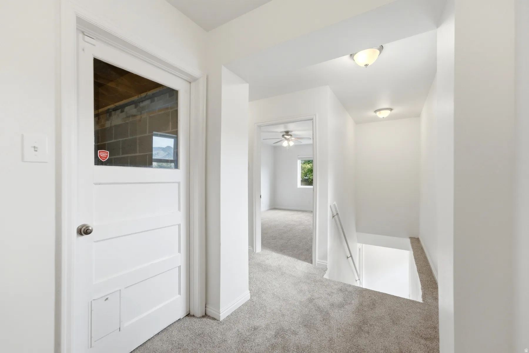 Hallway with recessed lighting, light-toned carpeting, and a white paneled door with a glass insert