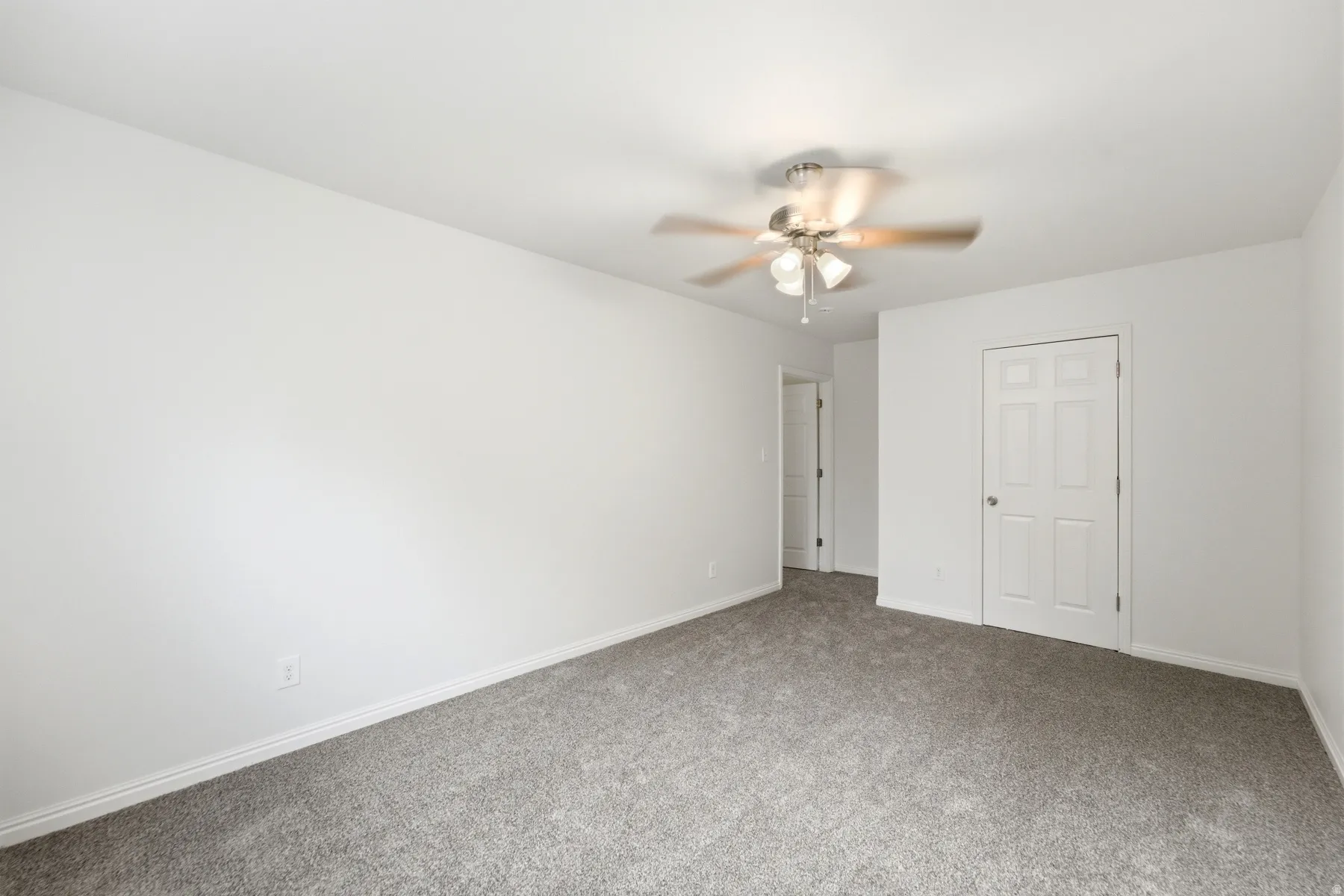 Neutral wall paint, ceiling fan with light fixture, paneled interior doors, and carpet flooring