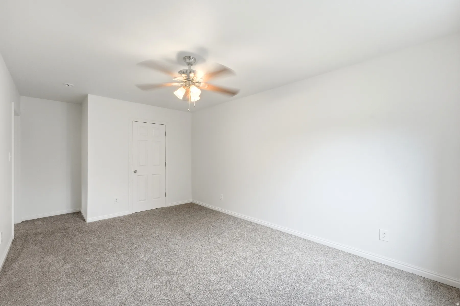 Gray carpeting, white walls, and a ceiling fan with light fixture