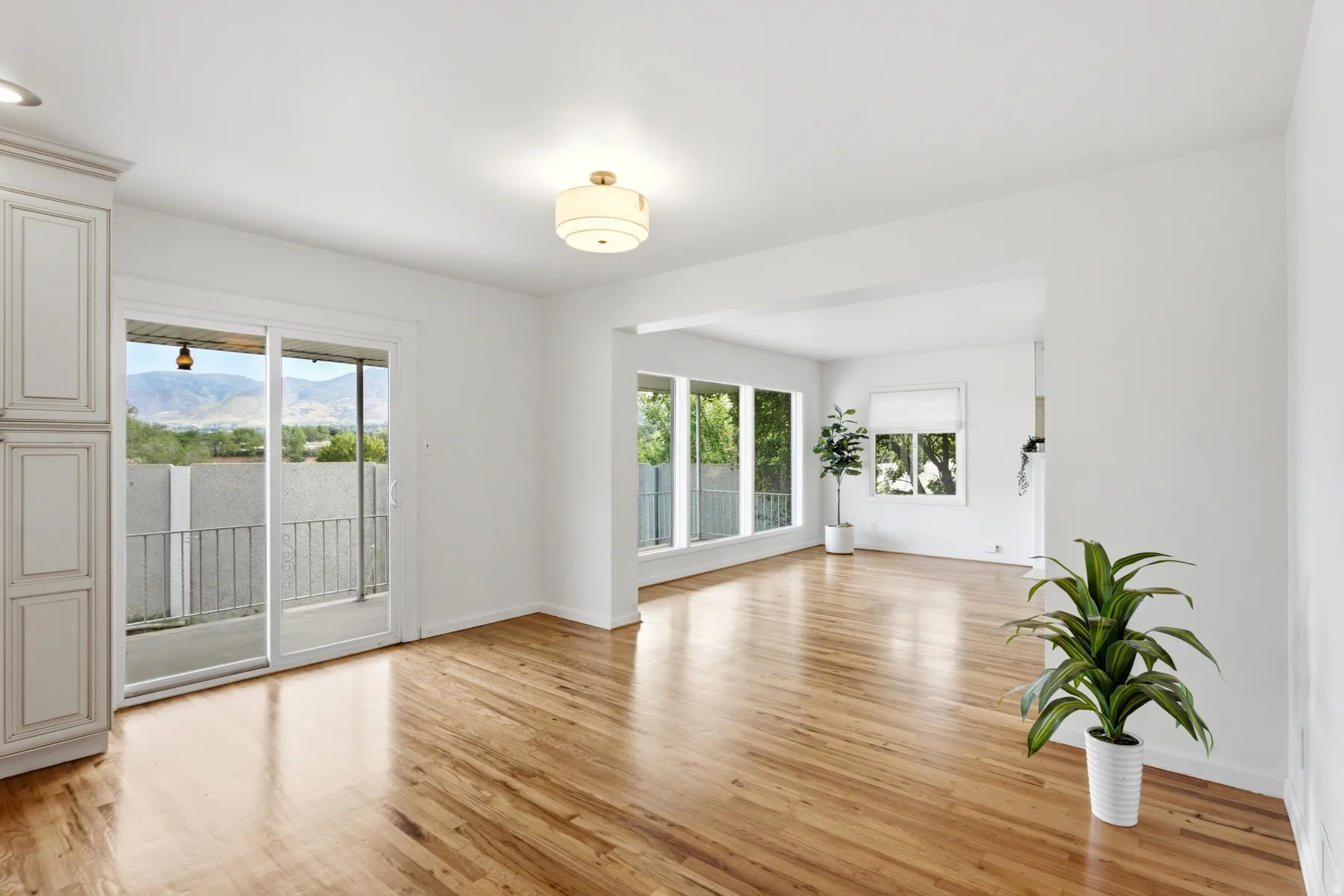 Hardwood flooring, expansive windows, white walls, built-in cabinetry, and a sliding glass door