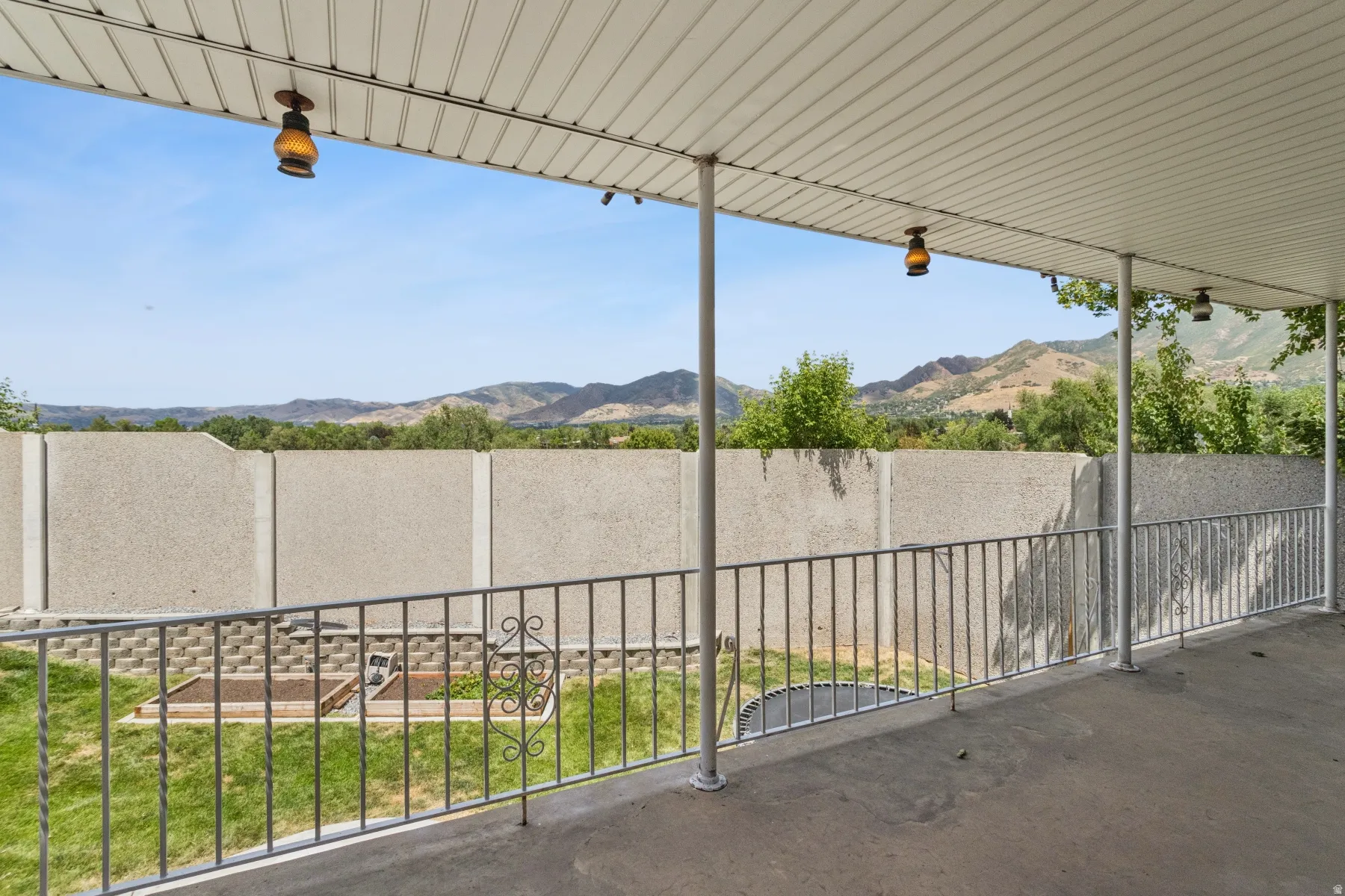 Covered concrete patio with metal railing and integrated ceiling lights