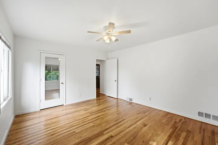 Hardwood flooring, white walls, and a ceiling fan with integrated lighting