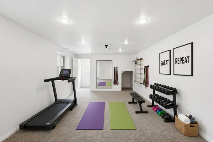 Recessed lighting illuminates this versatile space featuring carpeted flooring and a built-in shelving unit