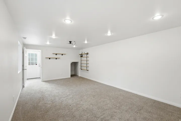 Recessed ceiling lighting, light-toned carpet flooring, built-in shelving, glass-paned door, and a built-in alcove