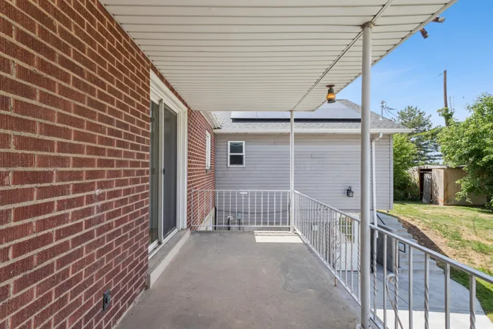 Concrete patio with a white metal railing, brick exterior, and an overhead lighting fixture