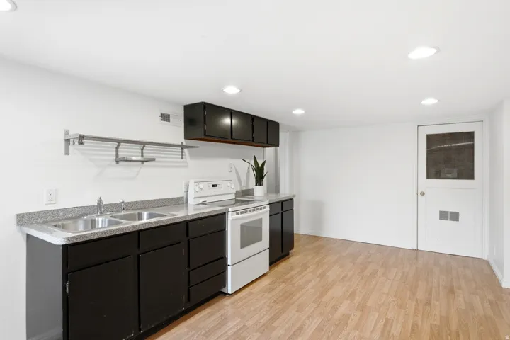 Full kitchen with dark wood-finish cabinetry, light-toned countertops, and wood-finish flooring