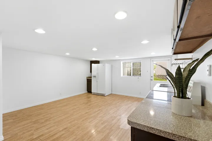 Expansive room with wood-finish flooring, recessed lighting, and a window for natural light
