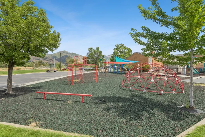 Recreational area featuring a geodesic dome, swing set, and climbing structure over a rubberized ground surface