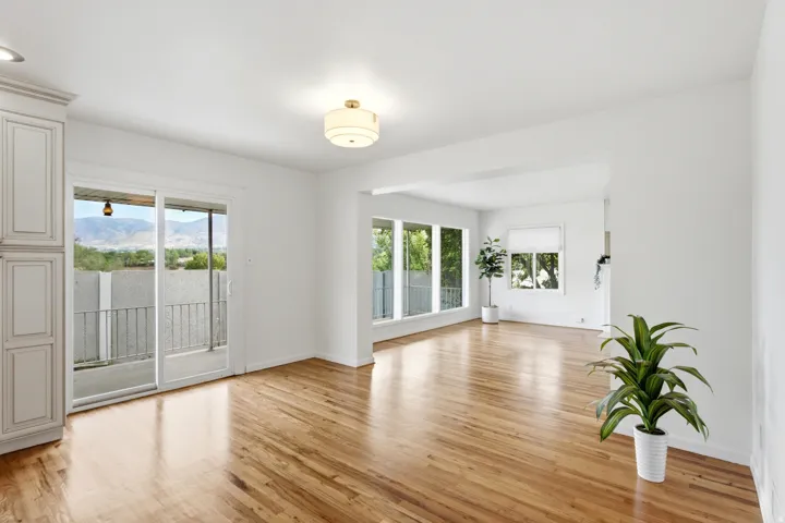 Hardwood flooring, expansive windows, white walls, built-in cabinetry, and a sliding glass door