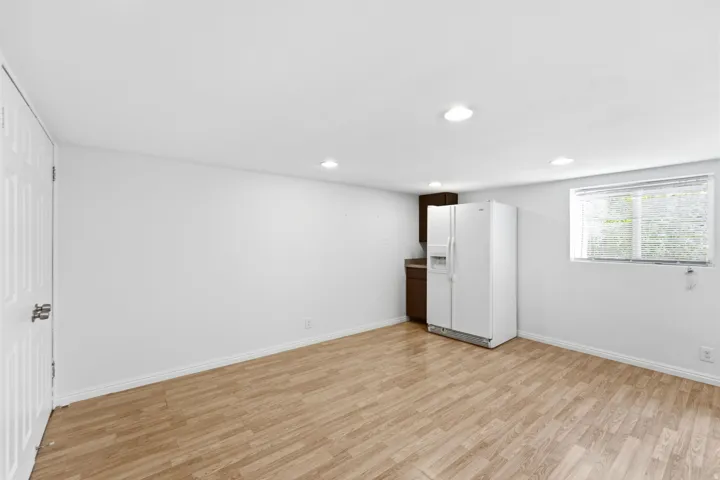 Recessed lighting, wood-finish flooring, built-in cabinetry, modern refrigerator, and a window with blinds