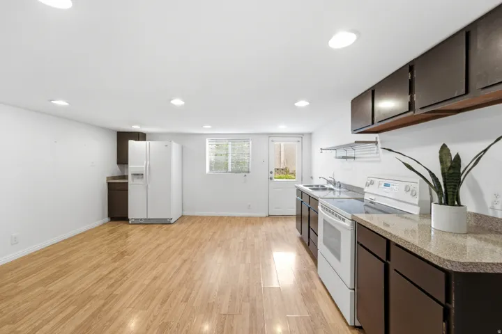 Bright kitchen area featuring wood-finish flooring, dark cabinetry, and light countertops