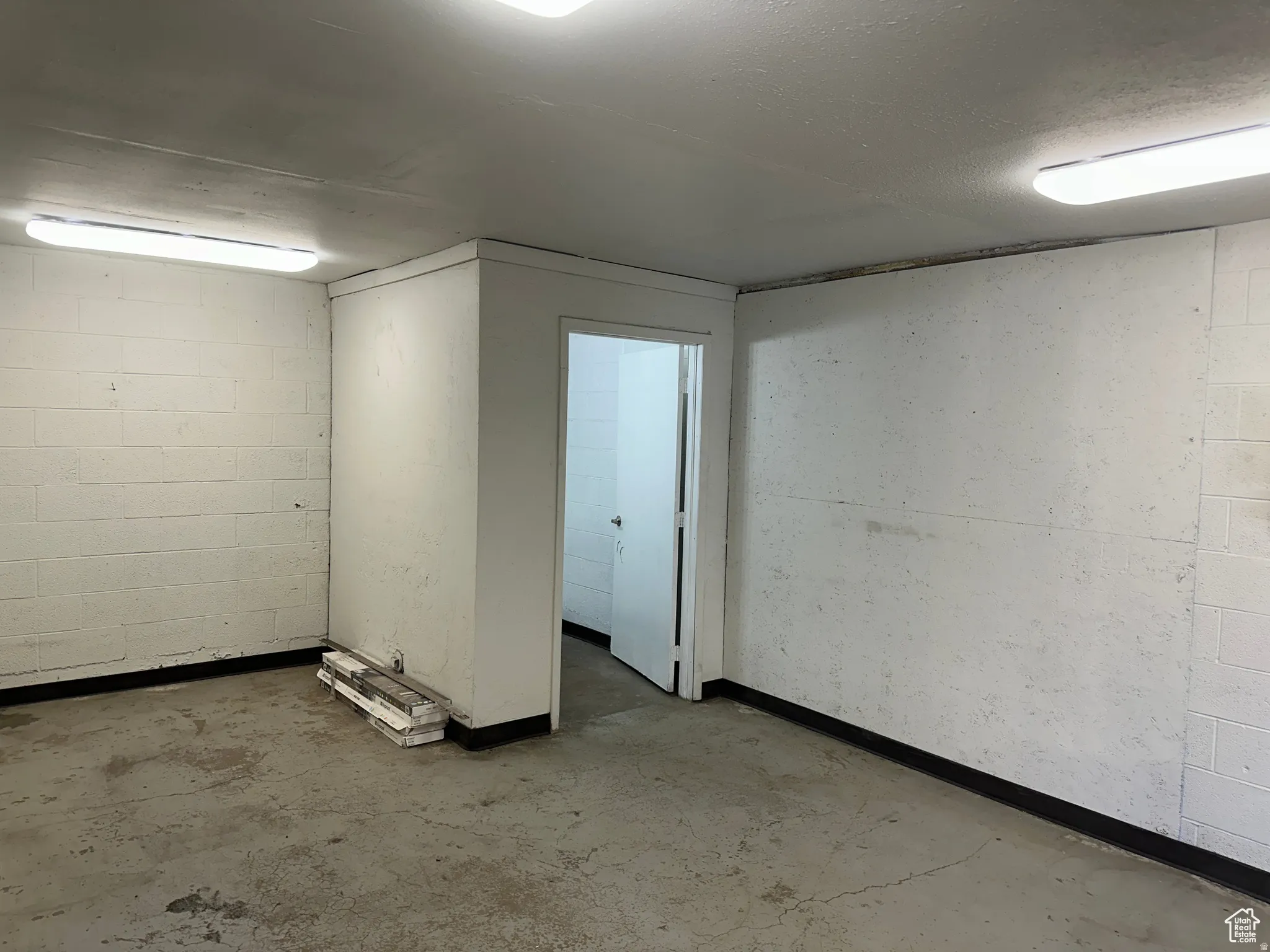 Concrete flooring, white block walls, recessed lighting, interior doorway