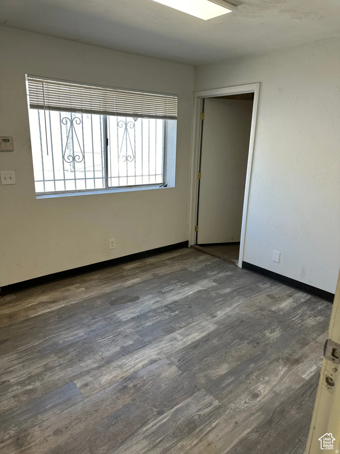 Wood-finish flooring, white wall paint, and a rectangular ceiling light fixture
