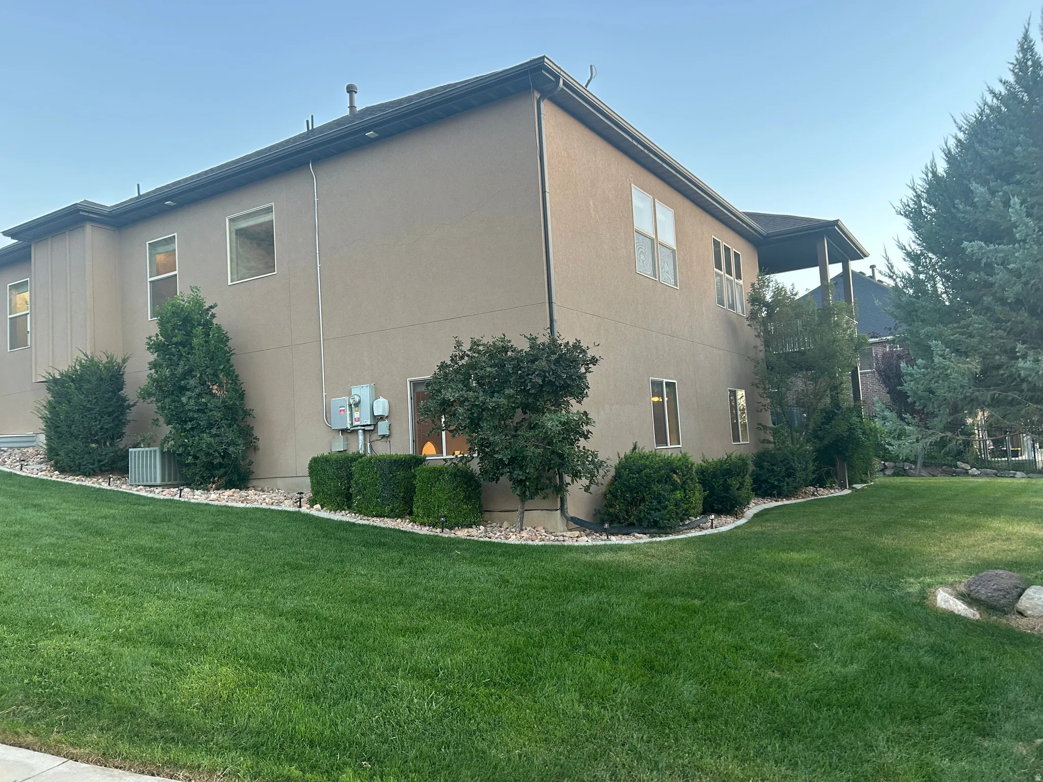 Expansive side yard featuring a manicured lawn, established shrubbery, and mature trees