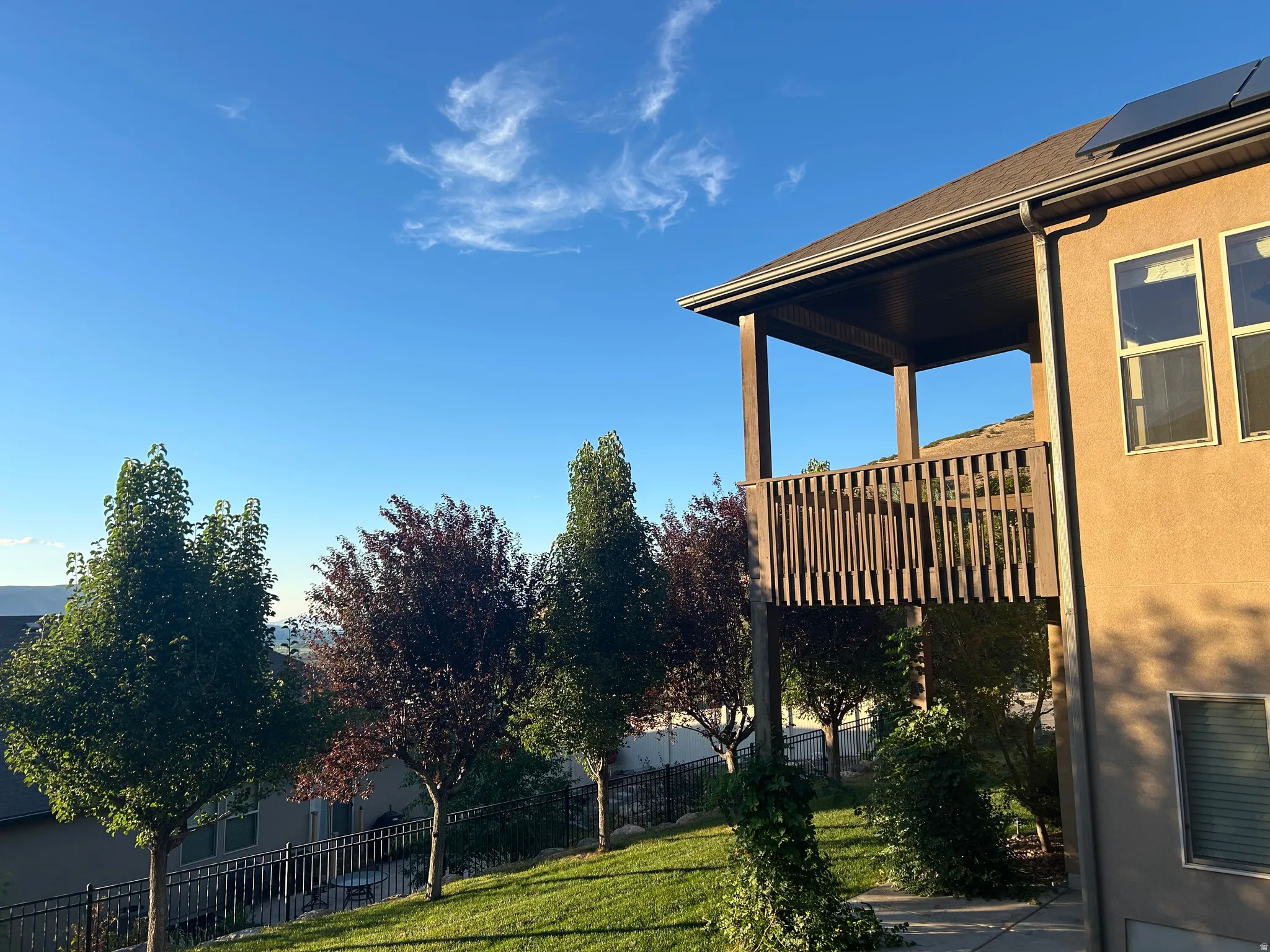 Covered outdoor deck with wood railing, stucco exterior, and solar panels